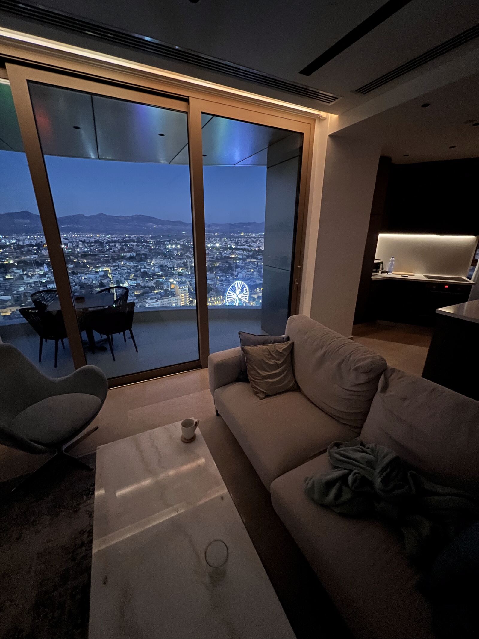 The living room of Ledra Sky at night, with the lights of Nicosia and the mountains through floor to ceiling windows